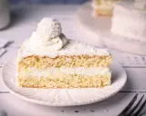 Ein saftiges Stück Raffaello Torte mit Kokosraspeln und Sahne, gekrönt von einer Raffaello-Kugel.