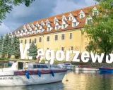 Węgorzewo atrakcje: malowniczy widok na port z łodziami i zabytkową kamienicą. Idealne miejsce na wypoczynek nad jeziorem.