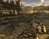 Pustynny krajobraz z ruiny miasta, gracz trzyma broń. W rogu ekranu widać tekst z gry, który sugeruje, że to **fallout new vegas spolszczenie**.