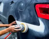 Mechanik szlifuje błotnik samochodu. Pytanie, czy benzyna ekstrakcyjna niszczy lakier, jest ważne przy takich pracach.