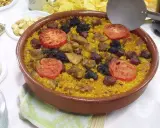 Un delicioso arroz al horno en cazuela de barro, con trozos de carne, chorizo, garbanzos y rodajas de tomate.