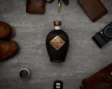Saigon Baigur Gin mit 43% Alkoholgehalt, umgeben von Lederaccessoires, Kamera und Schuhen.