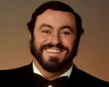 Uśmiechnięty Luciano Pavarotti w czarnym smokingu. Jego głos porusza serca, a jego uśmiech mówi "ti amo".