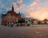 Rynek w Tarnowskich Górach o zachodzie słońca. Kolorowe chmury nad zabytkową zabudową i brukowanym placem.