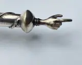 Manico in argento 325, cosa significa? Un dettaglio di un oggetto con una mano che indica.