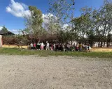 Niños y niñas posan en la granja escuela La Chopera, disfrutando de un día soleado rodeados de árboles y vegetación.