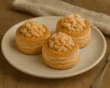Trzy puszyste vol-au-vent z krewetkami na talerzu, gotowe do degustacji.