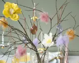 Vacker påskris inspiration med grenar dekorerade med glaskulor, tygblommor och fluffiga dekorationer i pastellfärger.