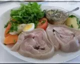 Tête de veau en cocotte, servie avec des légumes, un œuf dur et une sauce vinaigrette. Un plat traditionnel savoureux.