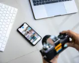 Aparat fotograficzny służy do uwieczniania chwil. Obok klawiatury, telefonu z Instagramem i laptopa, jest gotowy do pracy.