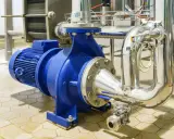 Pompe à eau industrielle bleue, connectée à des tuyaux en acier inoxydable. Un système essentiel pour gérer la pression eau maison.