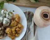 Talerz z klopsikami w sosie, pieczonym kalafiorem i ziemniakami, obok kokosa.