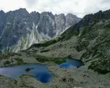 Dwa górskie jeziora odbijające niebo w sercu słowackich Tatr, otoczone skalistymi zboczami i zielenią.