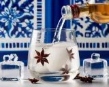 Ouzo wird in ein Glas mit Eis und Sternanis gegossen. Der Ouzo-Prozent-Gehalt ist hoch.