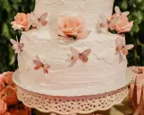 Gâteau à étages décoré de roses et de papillons, recouvert d'une délicate crème au beurre.