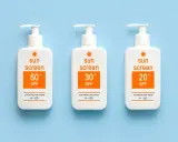 Trois bouteilles de crème solaire avec des indices SPF variés (50+, 30+, 20+). Le SPF signification est la protection contre les rayons du soleil.