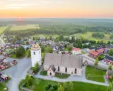 Gammelstad Luleå: en kyrka och ett kluster av röda trähus under en solnedgång.