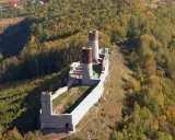Ruiny zamku Chęciny na wzgórzu, otoczone jesiennym lasem. Sprawdź zamek Chęciny cennik przed wizytą.