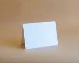 Biała kartka formatu B6 (12,5 x 17,6 cm) złożona na pół, gotowa na Twoje życzenia.