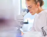 Ricerca scientifica per capire cos'è il sarcoma. Giovane scienziata al microscopio.