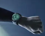 Un polso con un orologio dal quadrante luminoso, con indici e lancette che brillano grazie al super luminova, su sfondo blu scuro.