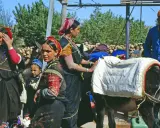 Berber Marokko Frauen mit Eseln, beladen mit Säcken. Ein Mann in blauer Jacke steht daneben.