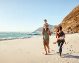 Glad familj på stranden. För att undvika att smittas av hepatit b, undvik delade personliga föremål.