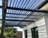 Ombre et lumière sur une maison moderne grâce à l'orientation des lames d'une pergola bioclimatique.