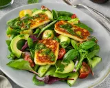 Pyszna sałatka z halloumi, awokado, pomidorkami i świeżymi ziołami, polana zielonym dressingiem.