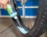 Flüssigkeit wird in einen MTB-Reifen gegossen, um ihn für den Tubeless-Betrieb vorzubereiten. Das ist ein wichtiger Schritt beim MTB Reifen wechseln.