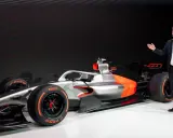 Ein Mann präsentiert stolz ein futuristisches Formel 1 Auto in Silber und Orange.