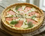Une délicieuse quiche au saumon, garnie d'aneth frais et de ciboulette, prête à être dégustée.