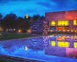 Abendstimmung am Museum mit reflektierendem Wasserbecken. Ein Turm leuchtet in der Ferne. Entdecke Bielefeld Geheimtipps!
