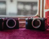 Dwa aparaty Sony Alpha, jeden a7c i drugi a7CR, leżą obok siebie na aksamitnym materiale.