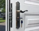 Detalle de varios tipos de cerraduras de seguridad en una puerta blanca, con una llave puesta.