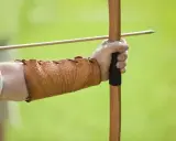 Mano con bracciale in cuoio, pronta a scoccare una freccia con l'arco, come un bellosguardo robin hood.