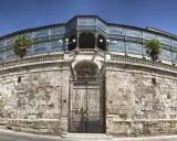 Edificio modernista en Salamanca con niños, palmeras y un cielo azul.