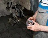 Mechanik trzyma nowe łożysko, przygotowując się do wymiany. Oto jak sprawdzić łożysko w kole przednim.