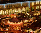 Vista aérea de mercadillos navideños iluminados, con un carrusel festivo y puestos de comida.