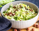 Frischer Chinakohlsalat mit gehackten Haselnüssen und Petersilie, serviert in einer Schüssel.