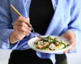 Kobieta je sałatkę z kurczakiem i serem feta, idealną na dietę 1200 kcal.