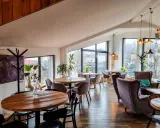 Przytulna restauracja w Bukowinie Tatrzańskiej z widokiem na góry. Drewniane stoły, wygodne fotele i stylowe oświetlenie tworzą ciepłą atmosferę.