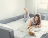 Mujer joven con su perro en un sofá cama bueno para dormir todos los días.