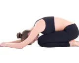 Frau in Kindhaltung, die bei Hexenschuss wie schlafen hilft. Entspannende Yoga-Pose für den Rücken.