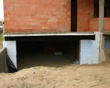 Budowa domu w toku. Widać fundamenty, ściany z pustaków zalewowych i izolację.