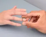 Manos unidas, un anillo dorado listo para ser colocado en el dedo anular, el lugar donde se pone el anillo de compromiso.