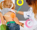 Medico esamina la schiena di una bambina, evidenziando possibili scoliosi sintomi.