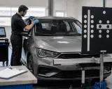 Mechanik w warsztacie przygotowuje samochód do wymiany szyby, używając specjalistycznego sprzętu.