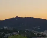 Silhouetten von Gebäuden auf einem bewaldeten barcelona berg im Abendlicht.