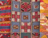 Bunte Teppiche mit geometrischen Mustern, die das orientalische Flair widerspiegeln. Ein Teppich zeigt Streifen, ein anderer Quadrate und das dritte Rauten.
